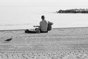 A lonely man playing guitar in a beach