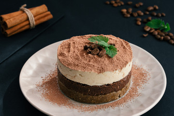 Tiramisu on a beige plate. Coffee with cinnamon. Raw dessert
