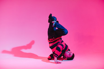 Young Man in a Jumper Dancing Contemporary Dance in Studio. Breakdancing. Dance School Poster. Copy Space. Battle competition announcement. Pink and Blue Background.
