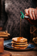 American pancakes with delicious mapple syrup on old wood table on a blue plate