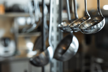 Metal inox ladles at a restaurant kitchen, blurred background