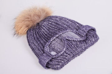 Fototapeta na wymiar Warm winter gray hat decorated with false ski glasses and fur on a white background