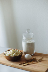cottage cheese in a wooden cup golden fork and spoon and egg on a wooden board