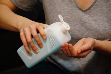 Woman pouring hand sanitizer disinfectant in her hand at home to avoid from corona viruses