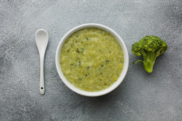Flat lay broccoli soup in bowl with spoon
