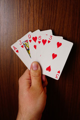 Poker cards with assorted combinations in man hand close up and isolated background