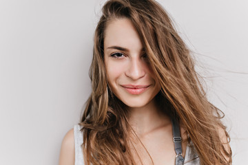 Close-up portrait of european woman with big dark eyes isolated on white background. Studio photo of charming girl with light-brown hair posing with smile.