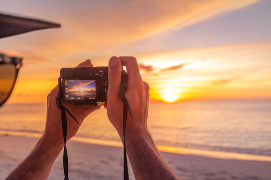Man holding camera, taking photo of summer beach. Photographers or travelers using a professional DSLR camera take photo beautiful sunset landscape, peaceful beach sunset.