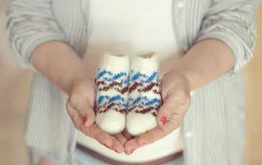 Knitted socks for the baby in the hands of a girl