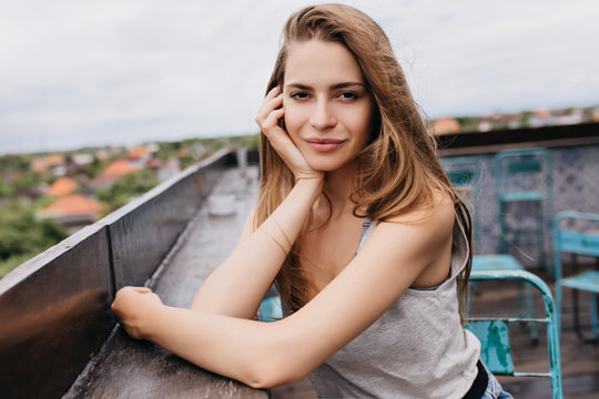 Pretty pale girl with romantic hairstyle spending time in roof cafe. Outdoor photo of amazing young woman chilling in spring weekend.
