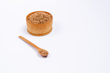Traditional Ukrainian dry unroasted buckwheat groats in a wooden spoon and bowl on a white background copy space.