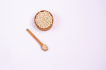 Dry white beans for vegans in a wooden spoon and bowl on a white background, copy space