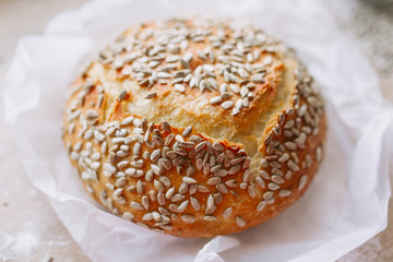 Freshly baked crusty bread in baking paper with sunflower seeds