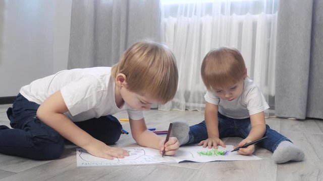 children draw with felt-tip pens in an album. little boy and girl concept childhood brother and sister play lifestyle paint on the floor with colored markers