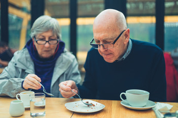 Mature couple drinking coffee and sharing cake in a cafe