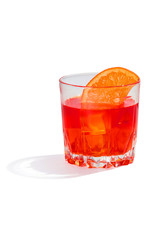 Negroni cocktail is contained in a low crystal glass with an orange slice and ice cubes. The showy illustrative picture is made on the white backdrop.