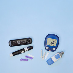 Diabetic kit: two types of glucometers, test strips, lancet. Top view, blue background, empty space.