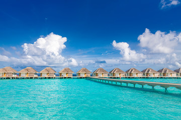 Water villas bungalows and wooden bridge at Tropical beach in the Maldives at summer day