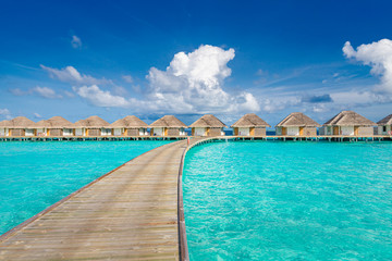 Water villas bungalows and wooden bridge at Tropical beach in the Maldives at summer day