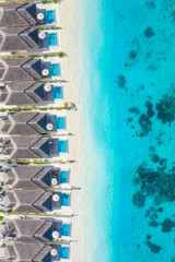 The drone photo with a wooden water villas seen from above and an amazing blue lagoon crystal clear water close to tropical lagoon. Amazing summer travel and vacation background. Dreamy beach scenery