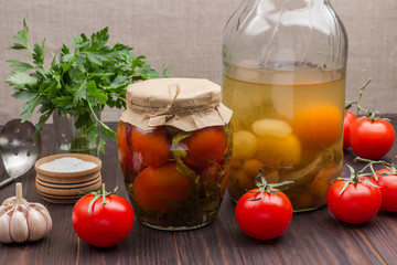 Obraz na płótnie Canvas Glass jar of canned tomatoes, fresh tomatoes, green parsley, garlic and spices