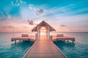 Amazing sunset landscape. Picturesque summer sunset in Maldives. Luxury resort villas seascape with soft led lights under colorful sky. Dream sunset over tropical sea, fantastic nature scenery - obrazy, fototapety, plakaty