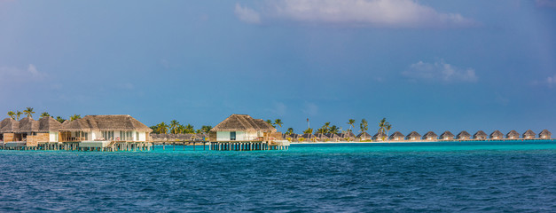 Panorama of Water Villas or bungalows and wooden bridge at Tropical beach in the Maldives at summer day