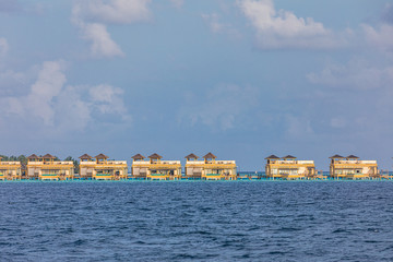 Fototapeta na wymiar Panorama of Water Villas or bungalows and wooden bridge at Tropical beach in the Maldives at summer day