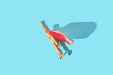 Movable human miniature model in red cape as a superman flies up.