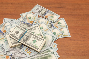 Many hundred dollar bills on wooden table background texture. bundles of money scattered on the...