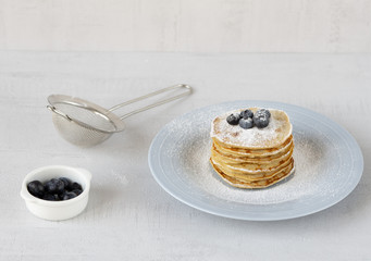 Delicious banana pancakes on a blue plate with blueberries and icing sugar. Milk. Close up. Healthy, sweet, eating, breakfast, snack. Vegetarian. Dessert, snack. 