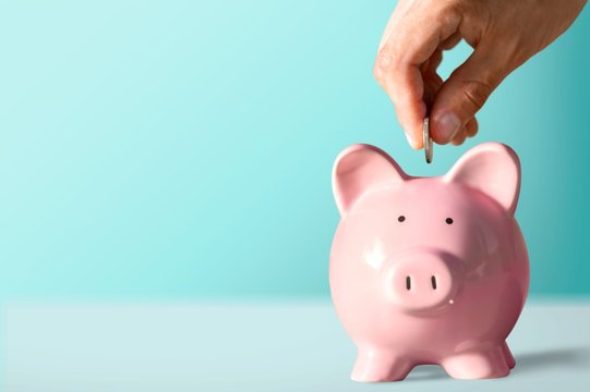 Businessman putting coin into the piggy bank