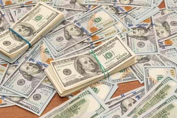 Many hundred dollar bills on wooden table background texture. bundles of money scattered on the office desk. wealth and income concept