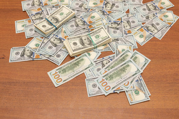 Fototapeta na wymiar Many hundred dollar bills on wooden table background texture. bundles of money scattered on the office desk. wealth and income concept