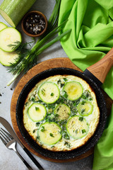 Breakfast. Summer omelet with zucchini and herbs on a stone or slate table. Top view flat lay.