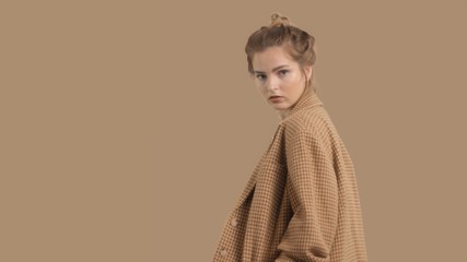 model in studio on brown background turns to the camera, oversize jacket fashion glamour look
