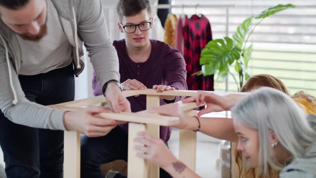 Young people assembling furniture in new home, house sharing concept.