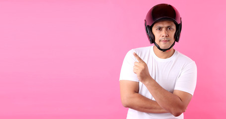 Asian man wearing a helmet motor and Pointing finger on empty space.on pink background in studio With copy space.