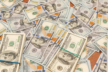 Many hundred dollar bills on wooden table background texture. bundles of money scattered on the office desk. wealth and income concept