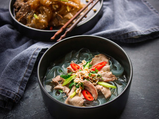 Asian cuisine, Vietnamese pho bo soup in a black plate on a dark background