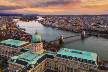 Fototapeta na wymiar Budapest, Hungary - Aerial view of Buda Castle Royal Palace with Szechenyi Chain Bridge, Parliament and colorful clouds at golden sunrise