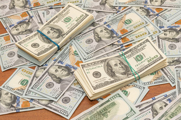 Many hundred dollar bills on wooden table background texture. bundles of money scattered on the...