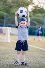 a little boy plays soccer in a city Park gives a pass kicks a ball