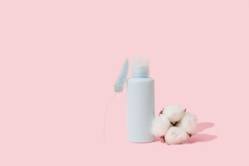 Blue container for cosmetic bottle with cotton flower, blank label for mock branding, Natural Beauty product concept. Pink background