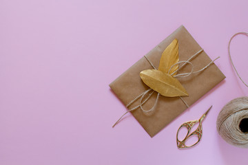 Light brown envelope with a gold feather for wedding invitations on a pink background. Flatley.
