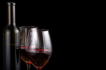 two glasses and bottle with red wine on black