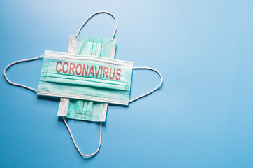 Green medical face mask on blue background with Coronavirus on it