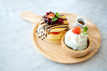 A mixed berries pancakes with ice cream and whipped cream in wooden plate