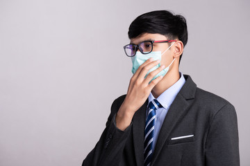 Fototapeta na wymiar Close up of a businessman in a suit wearing Protective face mask, get ready for Coronavirus and pm 2.5 fighting against gray background. Healthcare concept.