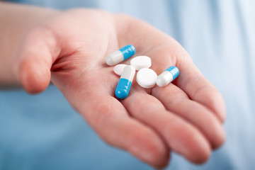 Close up of medical pills and capsules in the palm of a caucasian woman